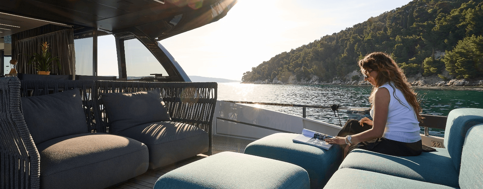 Relaxing on board a yacht - a woman with a book against the backdrop of a picturesque bay